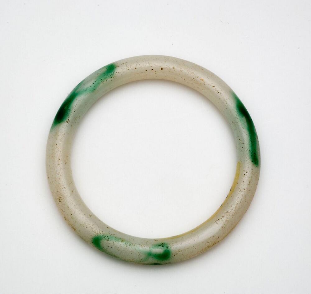 Armring of white glass with some dark green spots