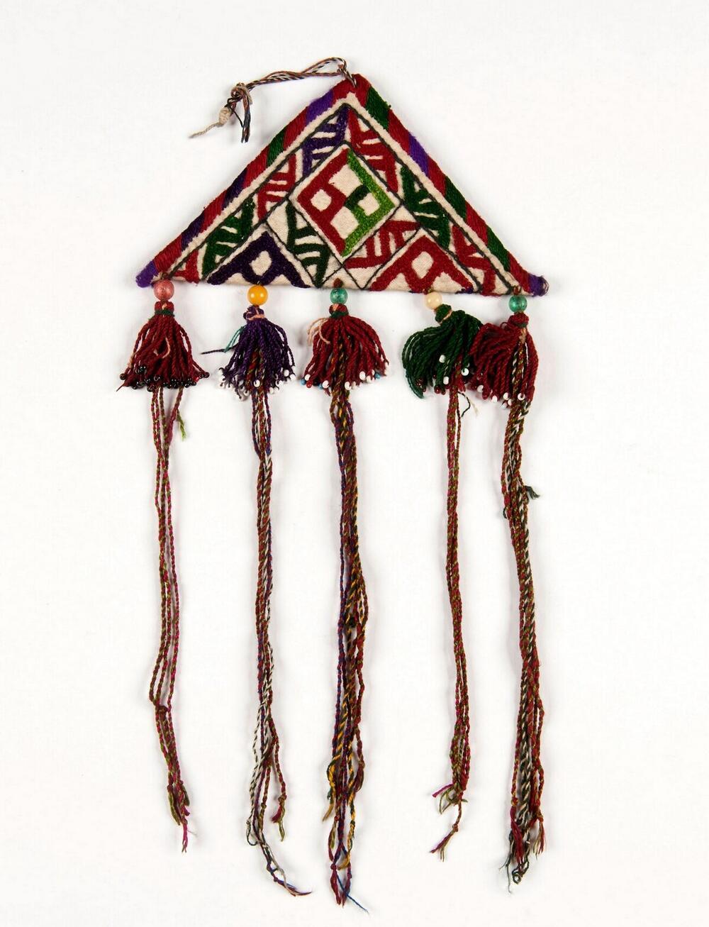 Amulet van textiel met patronen en kwastjes versierd