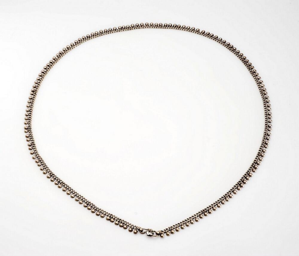 Zilveren schakelketting, over de rok rond het middel gedragen door moslim vrouw