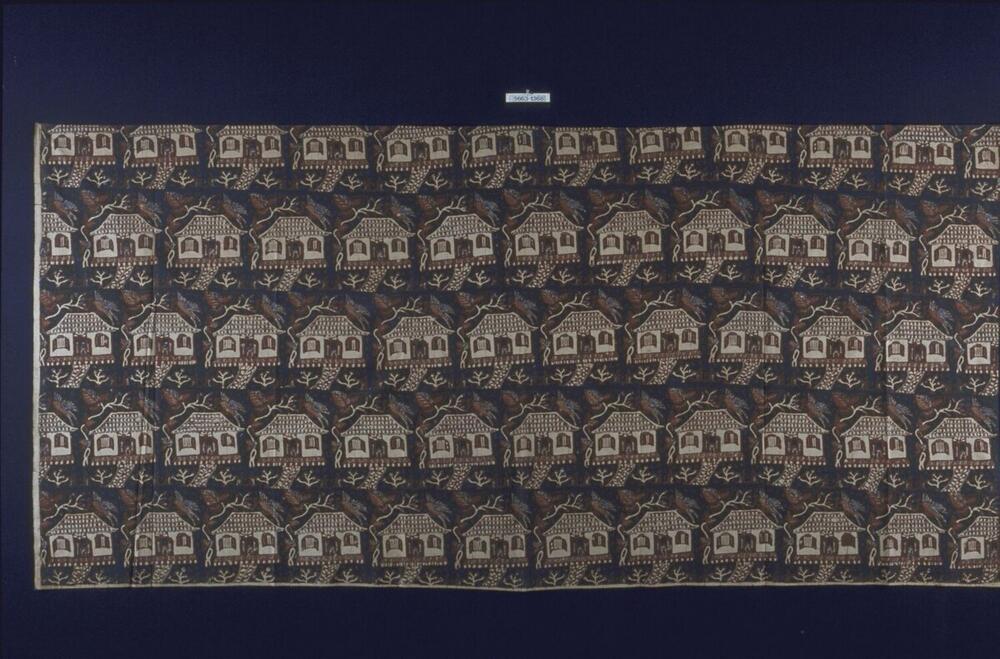 Wikkelrok met geometrisch patroon van huizen, bomen, vogels en figuren in de deuropeningen