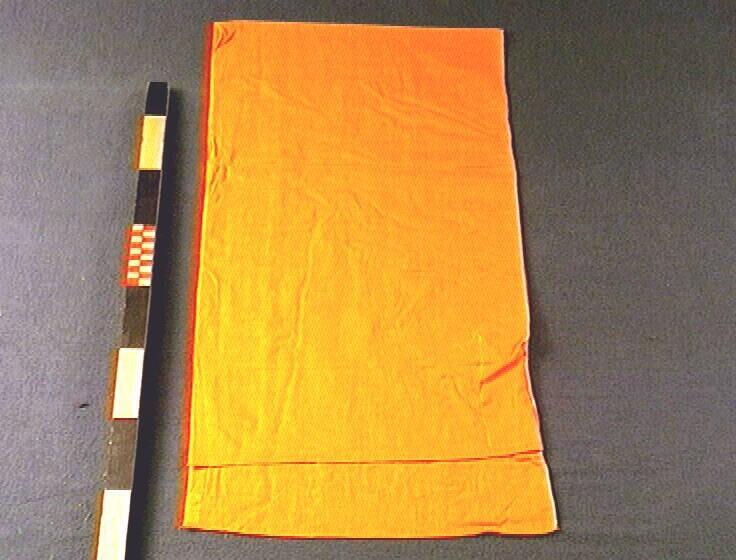 Een oranje mousseline vest, onderdeel van een zesdelige set kleding voor een monnik.