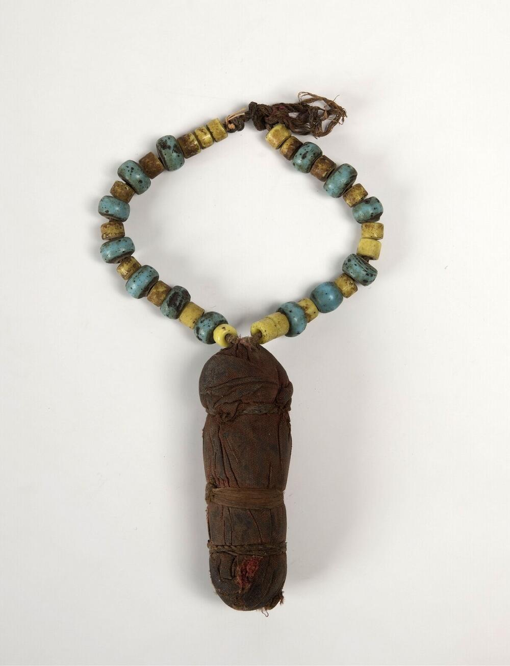 Amulet wrapped in red cotton, on a necklace of glas beads