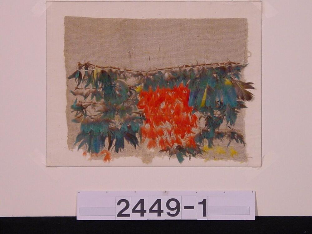 Fragment van een wollen poncho met versiering van veertjes