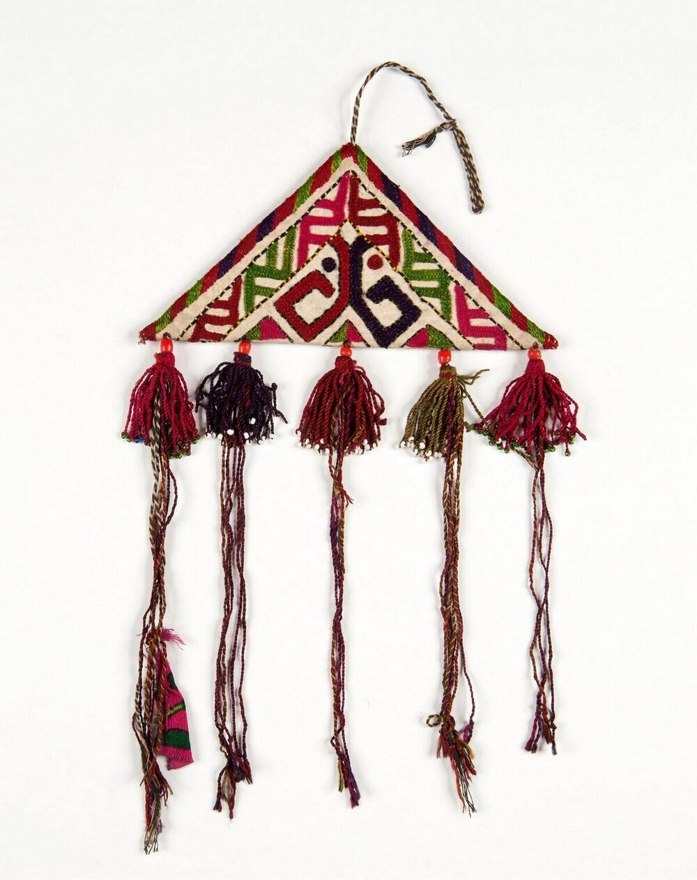 Amulet van textiel met patronen en kwastjes versierd