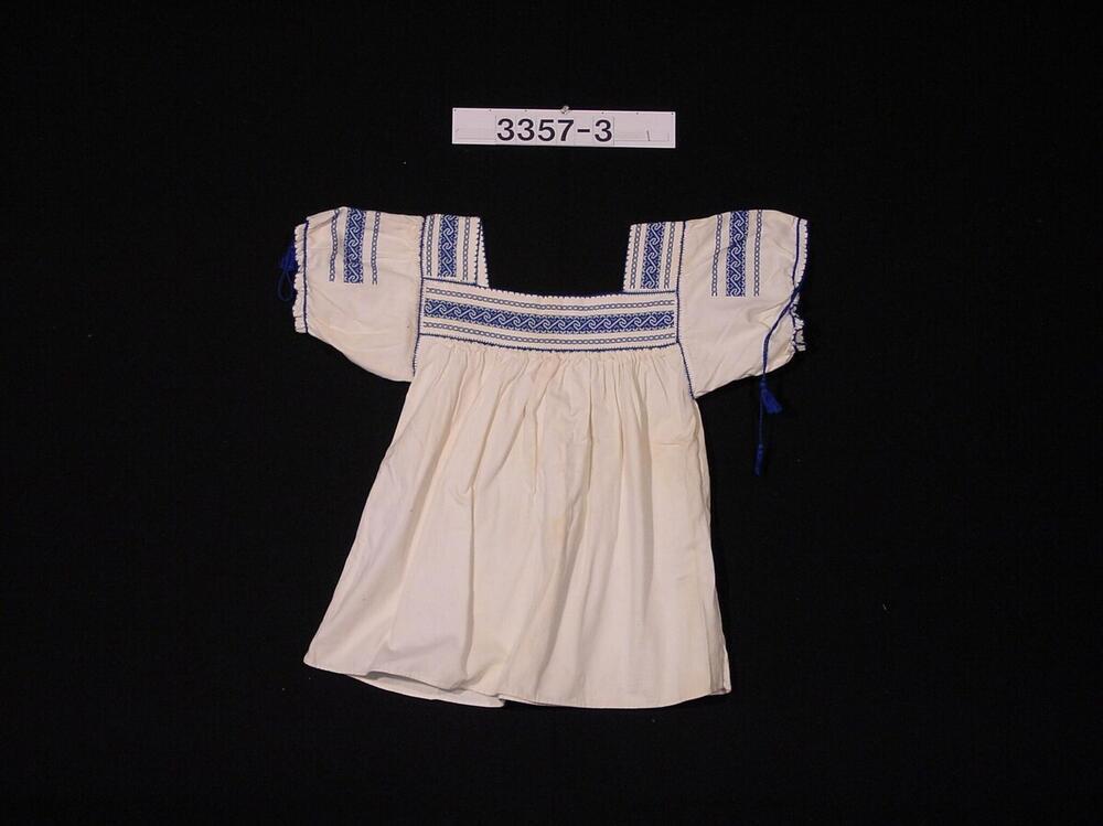 Witte vrouwenblouse met blauw borduurwerk aan hals en mouwen
