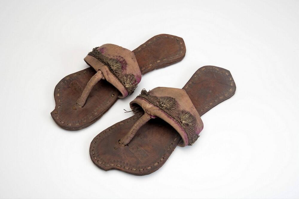 Een paar leren slippers met geborduurde flanel band