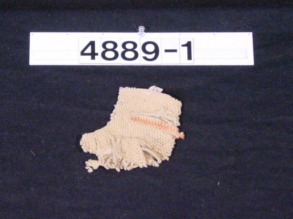 Fragment van een beige sokje van wol met oranje dwarsrandje