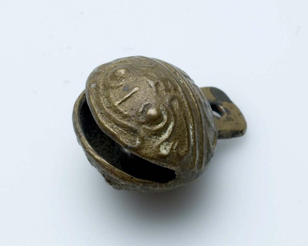 Messingen belletje in de vorm van een kikkerkop, door kinderen aan de pols gedragen en tevens amulet