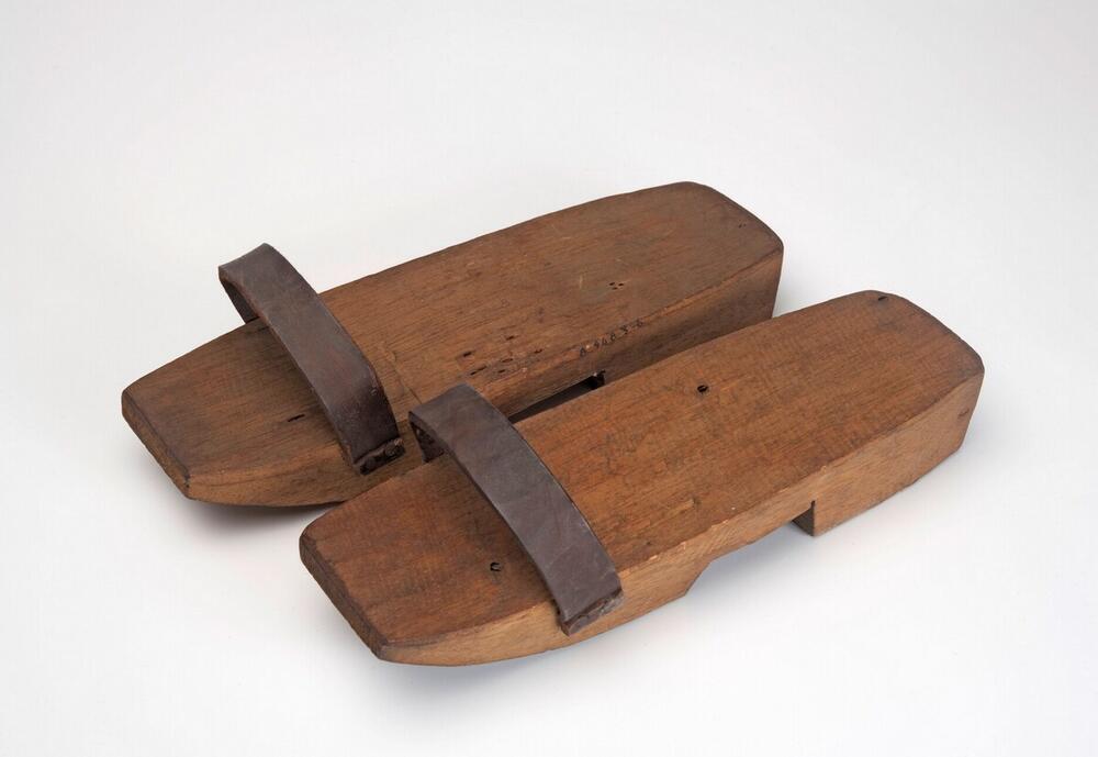 Een paar houten slippers met leren band
