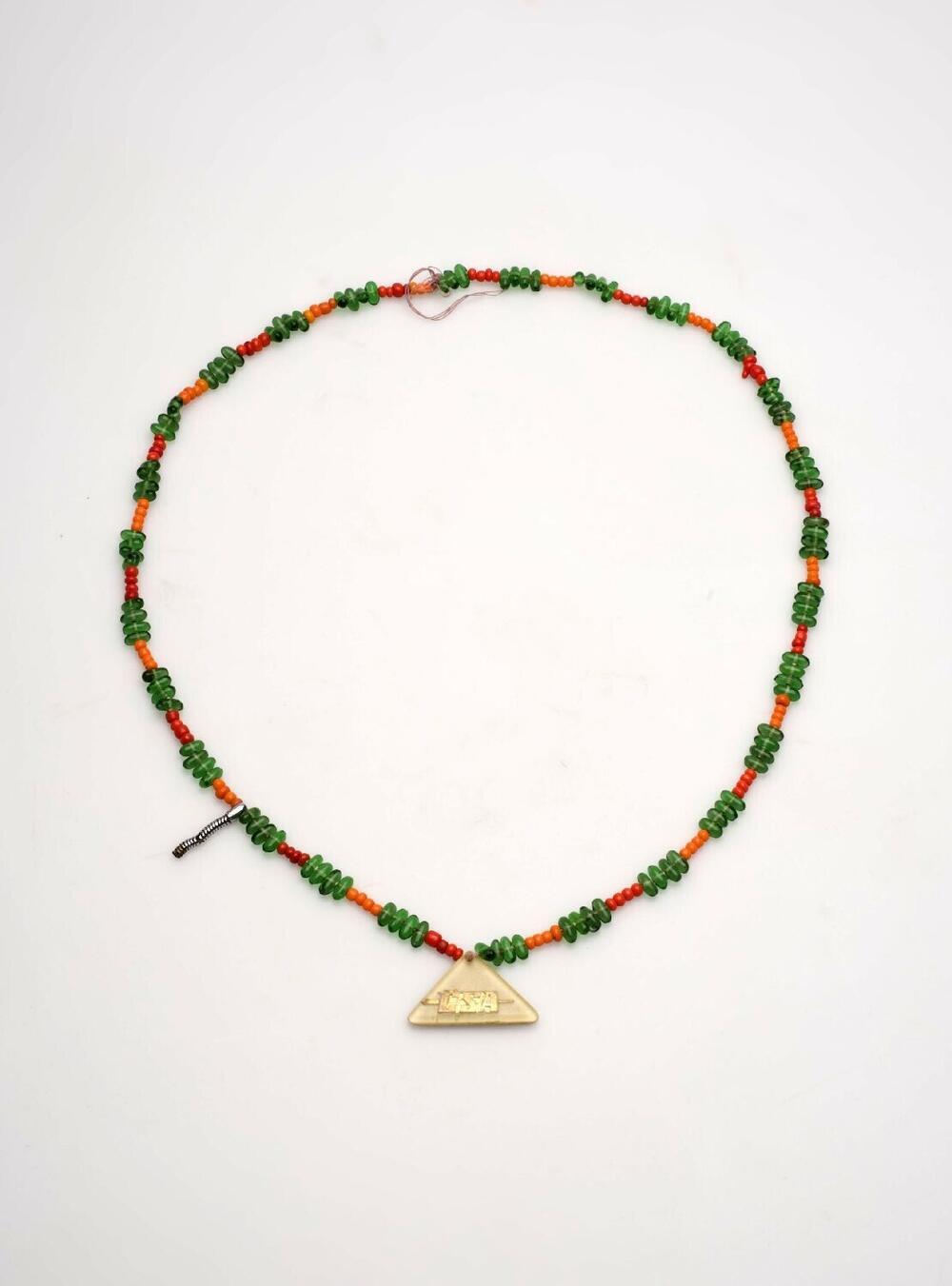 Halssieraad met groene en rode kralen en driehoekige hanger met daarop de letters CSA