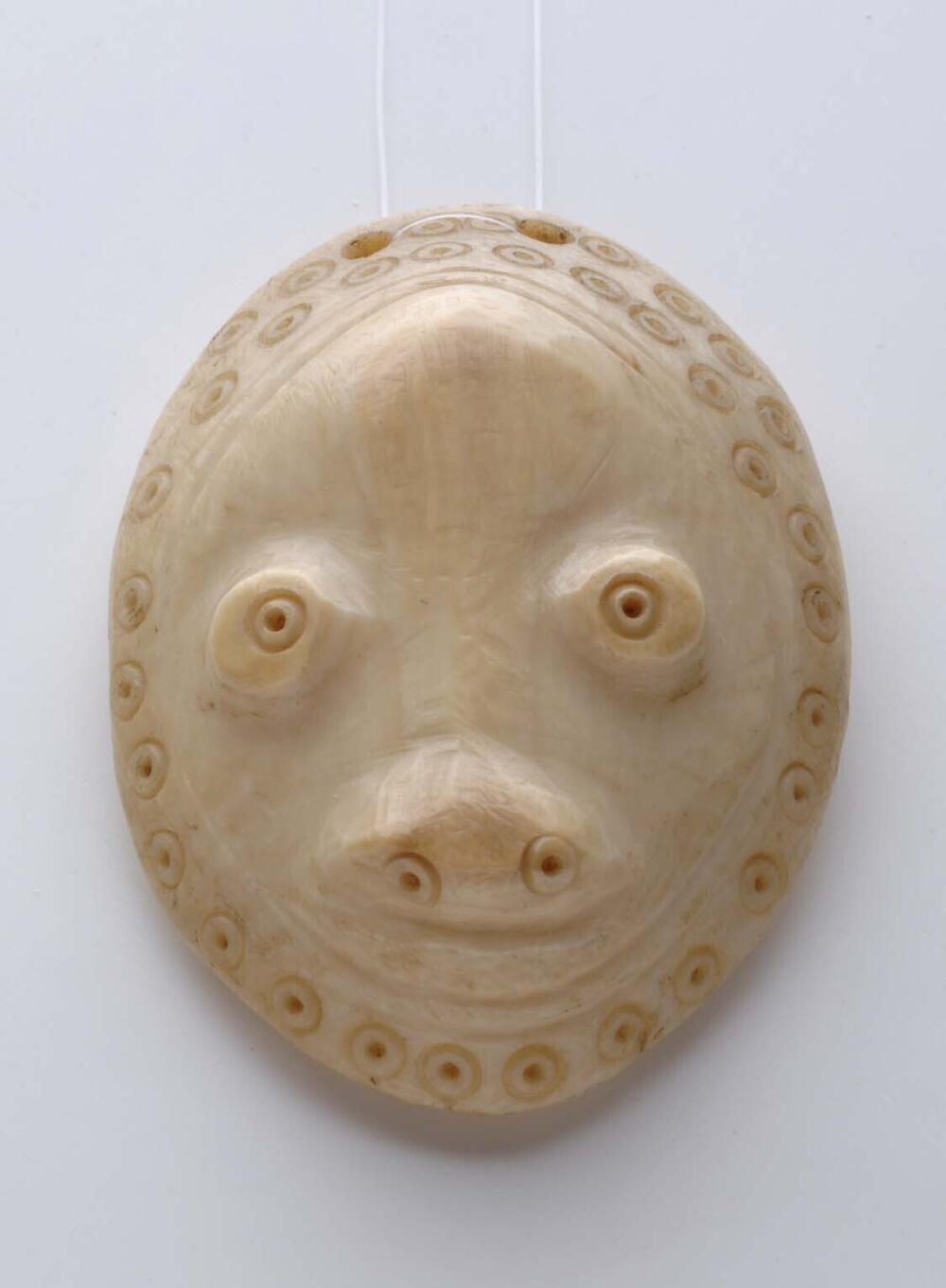 Ivoren hanger in de vorm van een miniatuurmasker