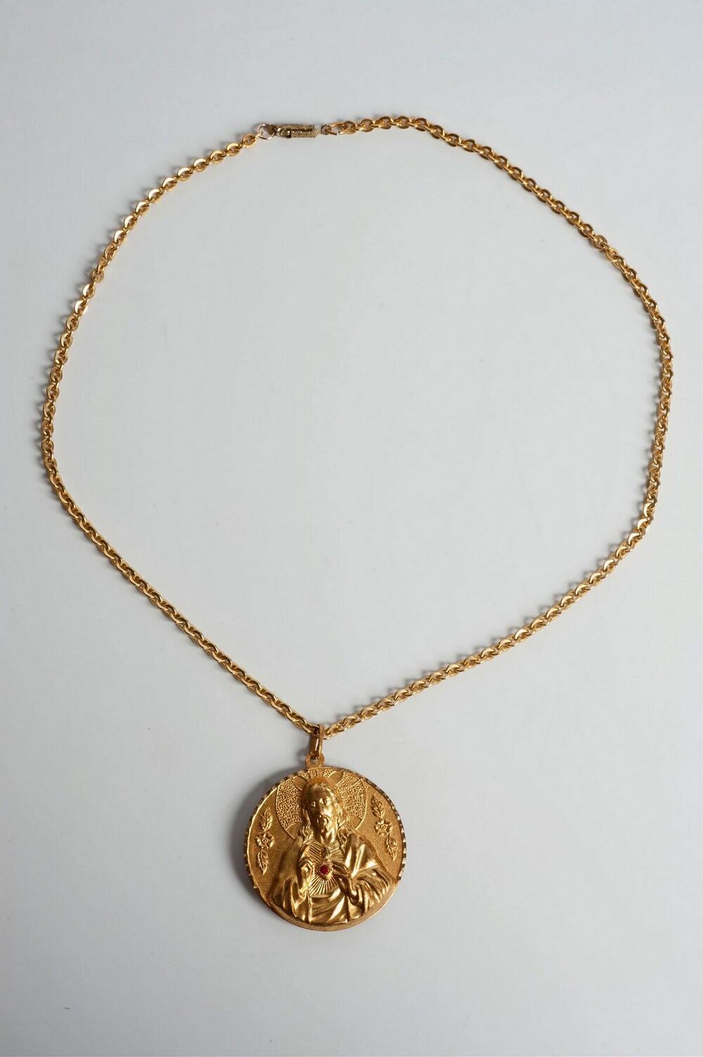 Goudkleurige schakelketting met medaillon met een afbeelding van Jezus Christus en aan de andere…