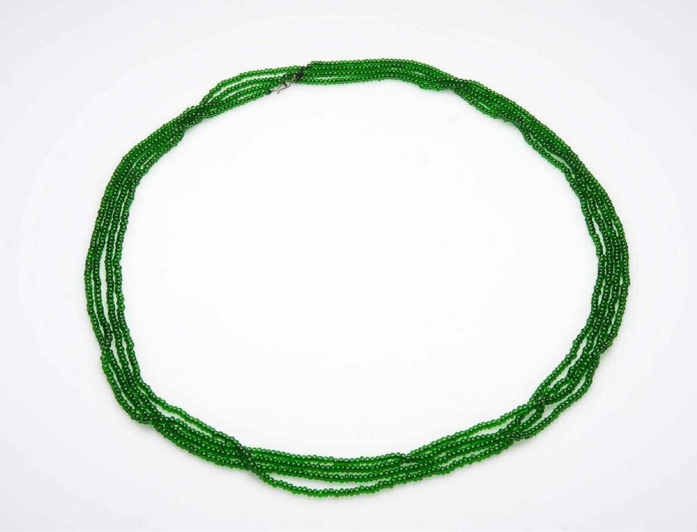 Zeer lange ketting van groene kralen, die meerdere malen rond de hals gedraaid wordt