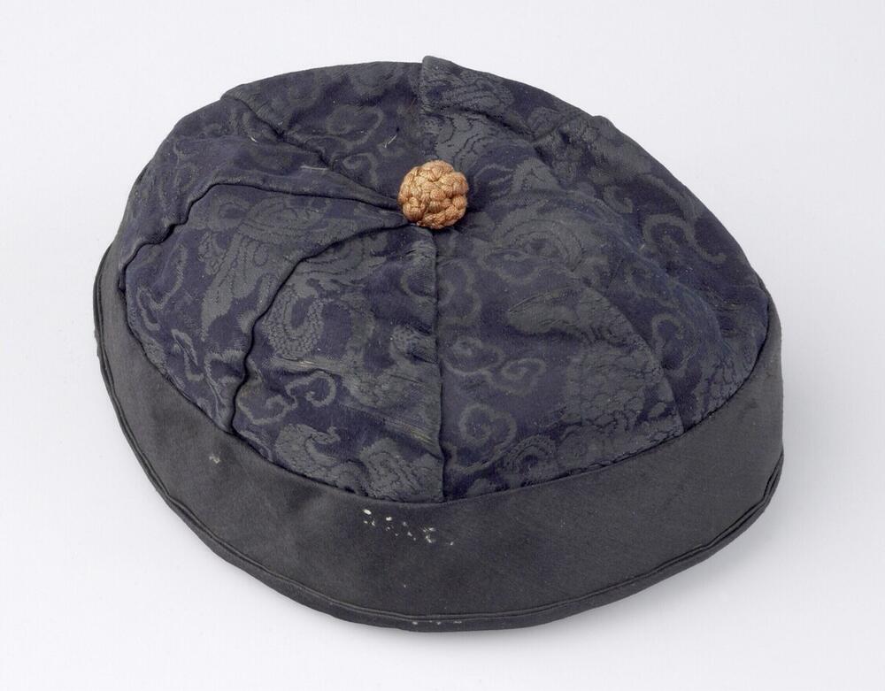Muts van donkerblauwe en zwarte gebloemde zijde met oranje knop