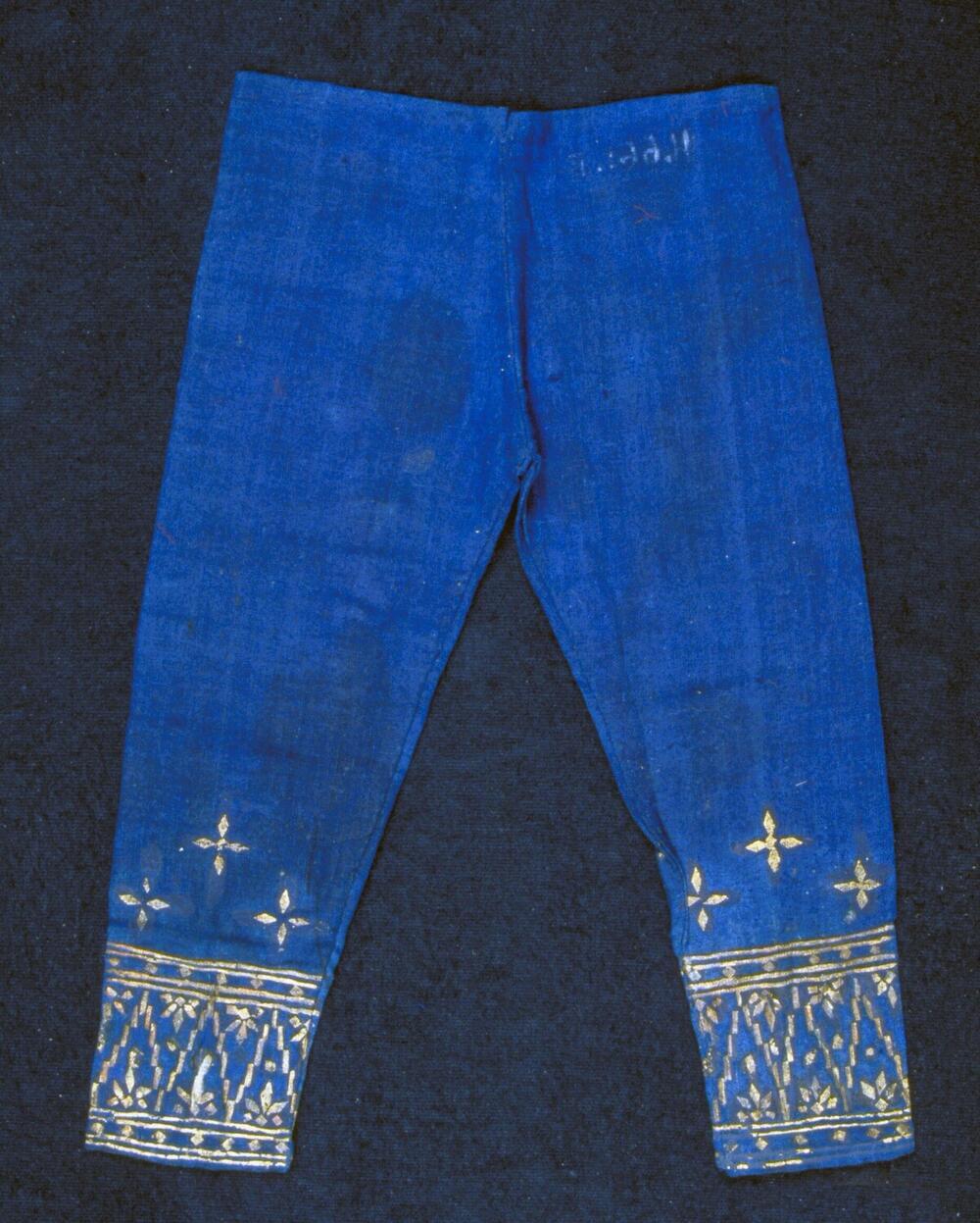 Broek voor een pop in een tentoonstelling, bedrukt met gouden tumpal-motieven