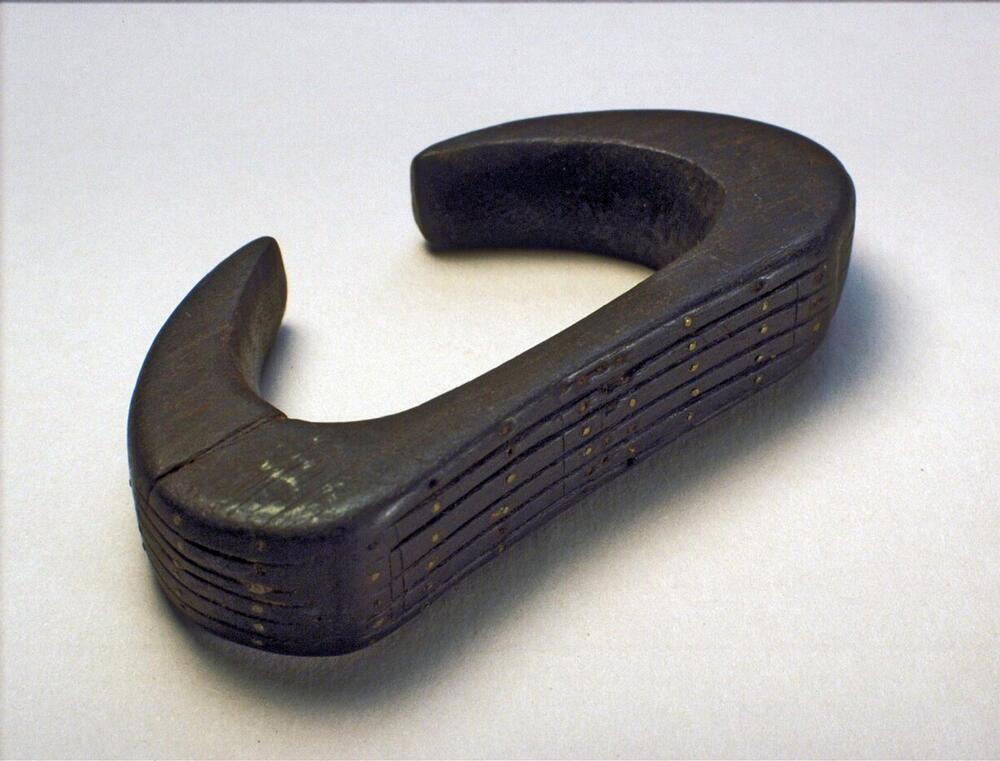 Houten armband, versierd met rondgaande groeven en koperen stippen in zigzag motief