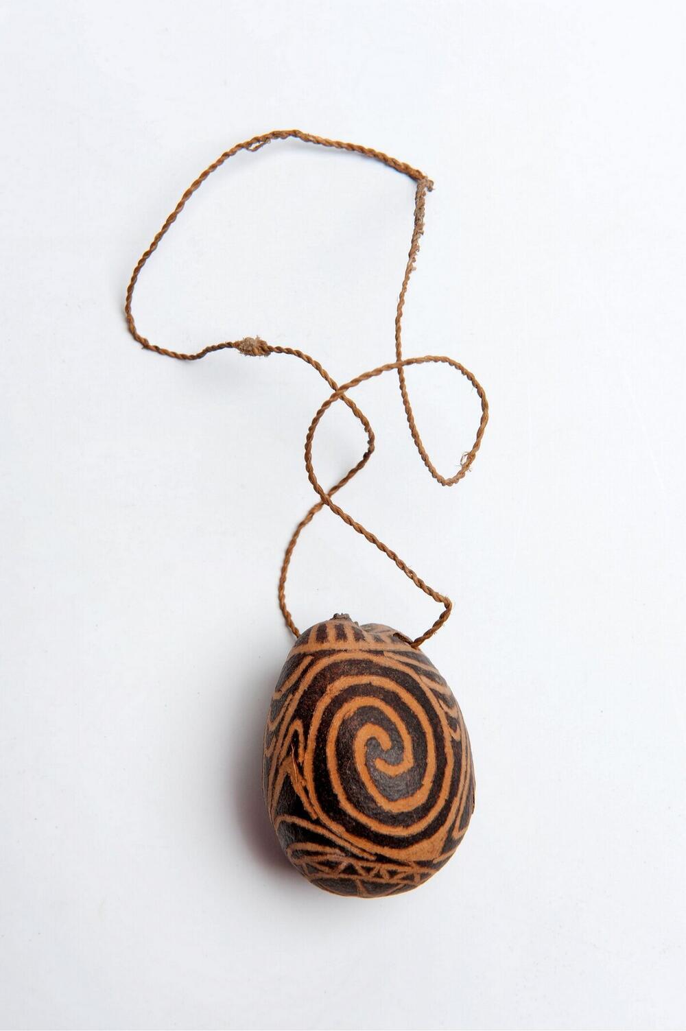 Versierde noot (amulet) aan een draagkoord