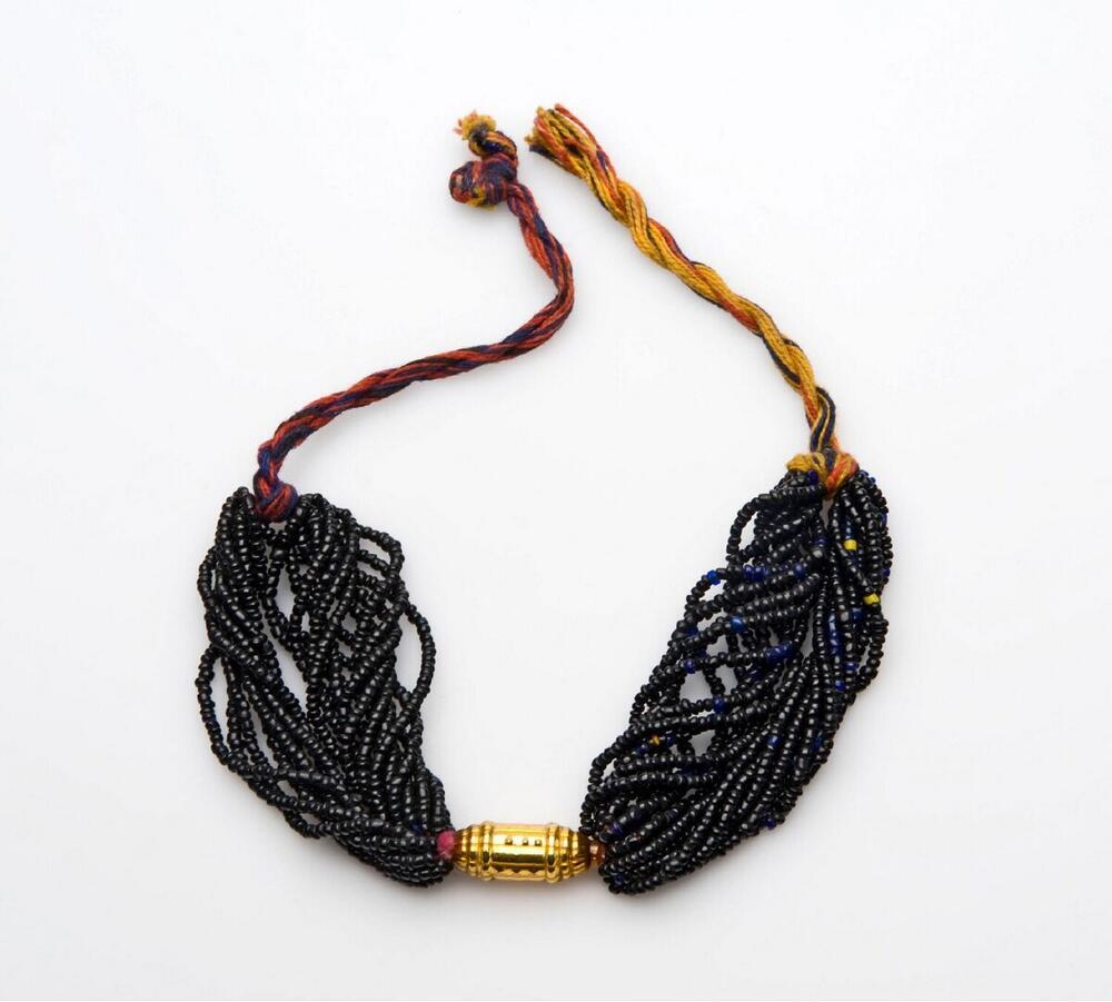 Ketting van zwarte plastic kralen en blikken ornament