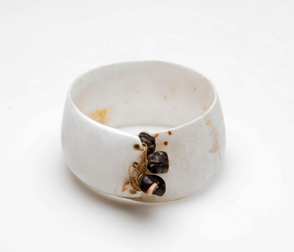 Armband uit schelp geslepen en met zwarte zaden versierd