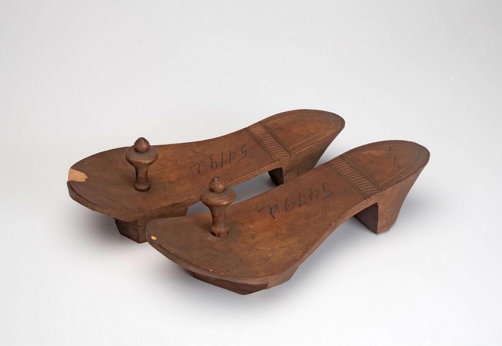 Een paar houten slippers met houten knoppen
