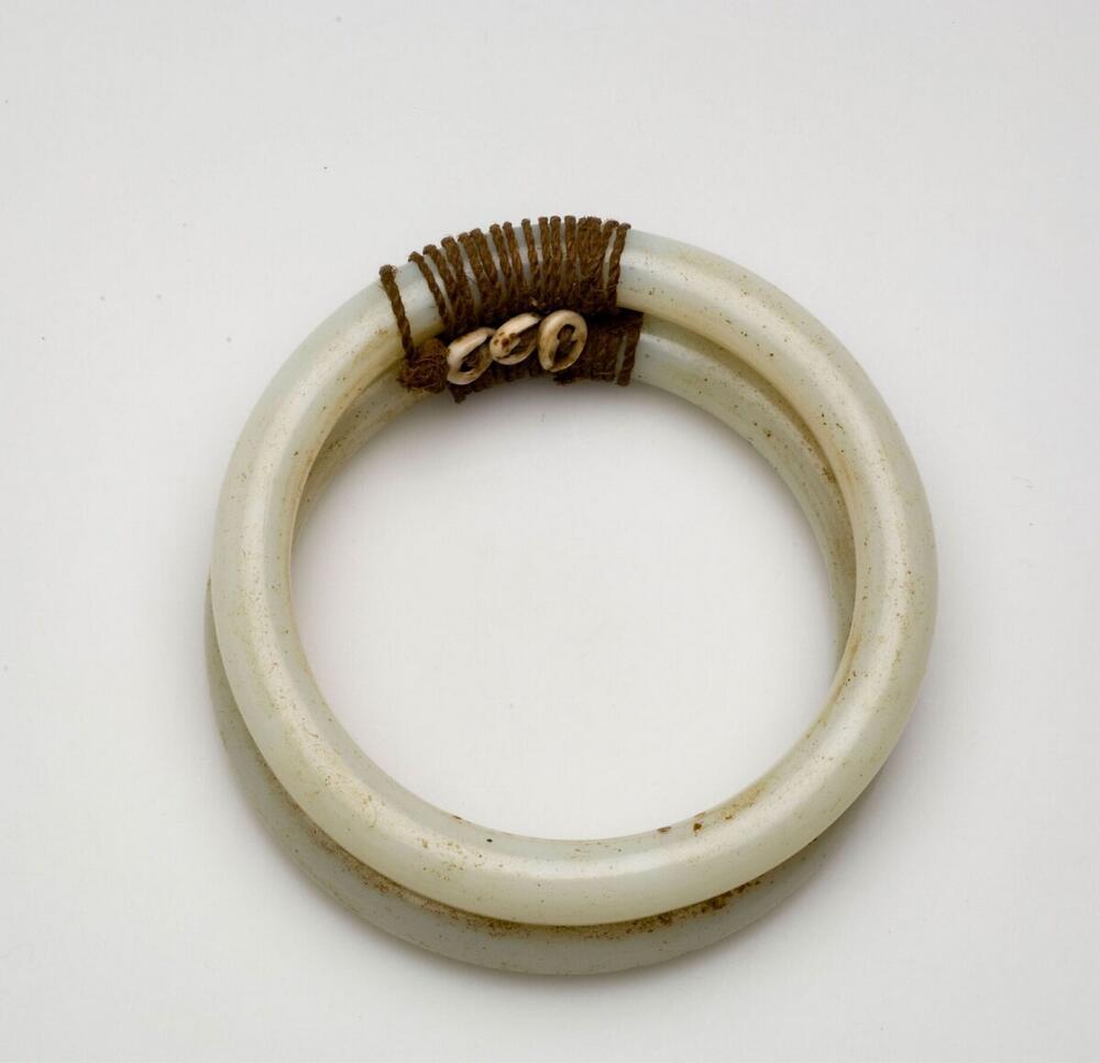 Two armrings of white glass, bound together with fibre