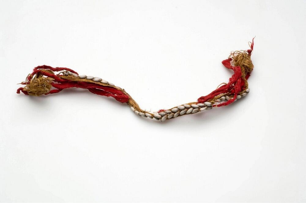 Knieband, versierd met rood katoen en coïxpitten