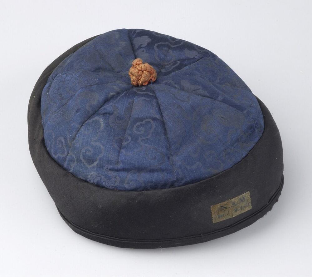 Muts van blauwe en zwarte zijde met oranje knop