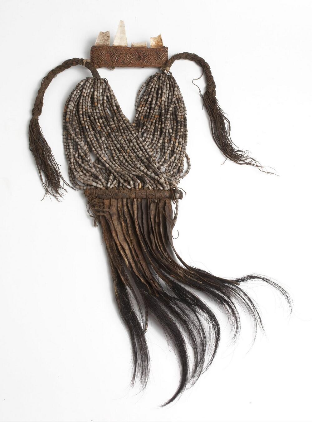 Breast ornament, made of braided fibers and decorated with beads, hair and skin