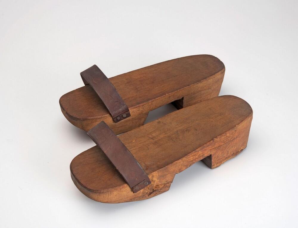 Een paar houten slippers met leren band
