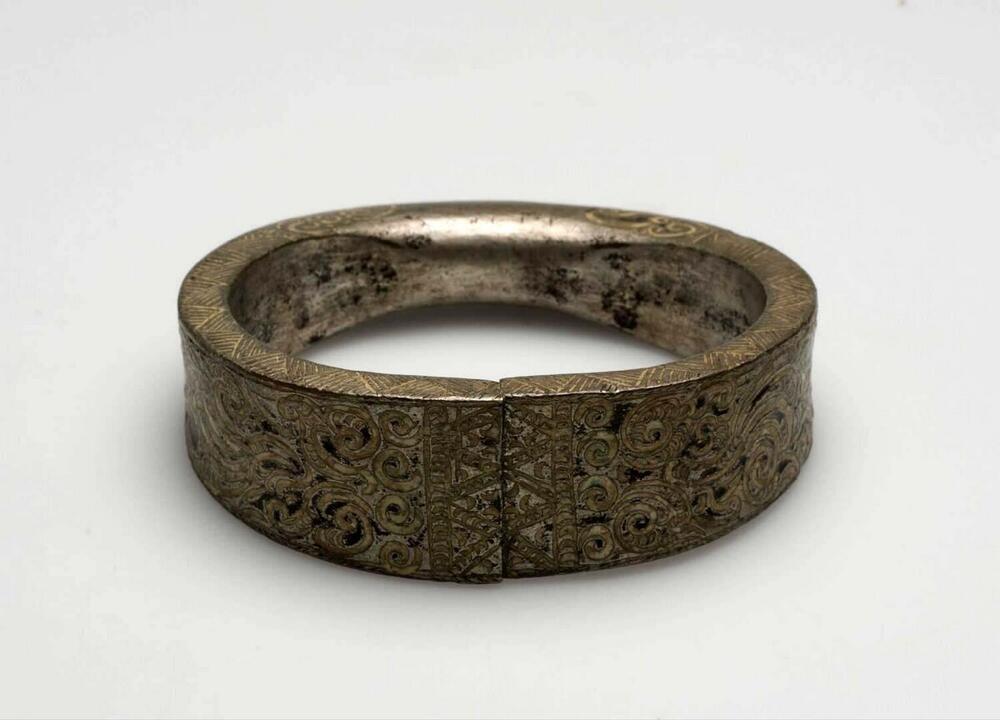 Metalen armband versierd met ciseleerwerk, onderdeel van een paar