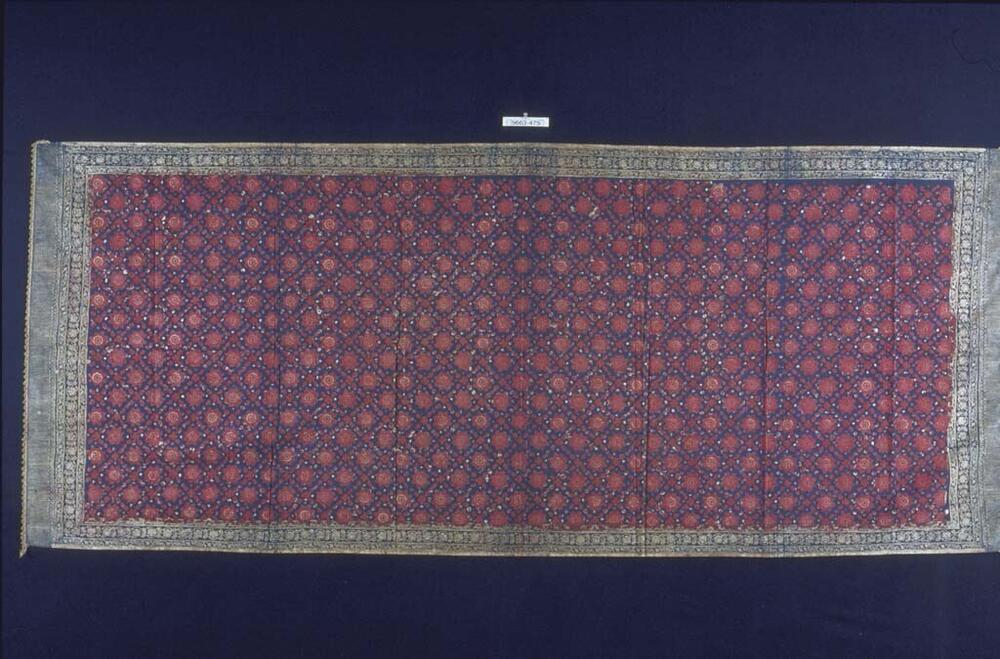 Katoenen schouderdoek met geometrische motieven, waarvan de rand is afgewerkt met gouddraad