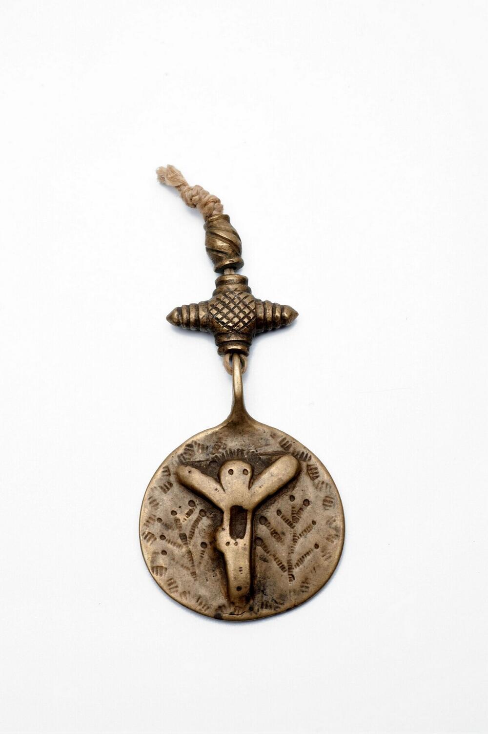 Messingen hanger of amulet met vermoedelijk een Christusfiguur