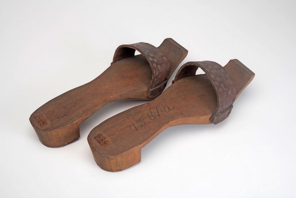 Een paar houten slippers met leren band