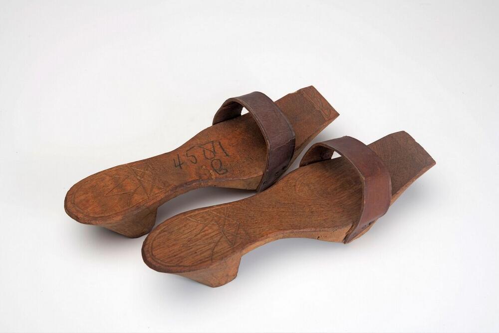 Een paar houten slippers met leren band