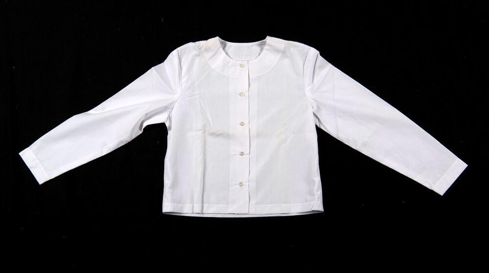 Een witte katoenen blouse, onderdeel van een driedelige kledingset van een non.