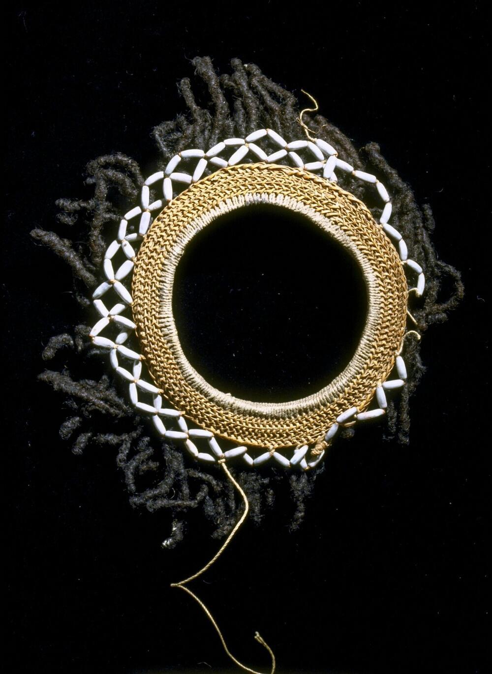 Armband van gevlochten rotan met versiering van coixpitjes en mensenhaar