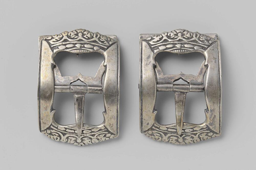 Schoengesp van zilver, waarvan de zijkanten de vorm van een kroon hebben, in vlak reliëf
