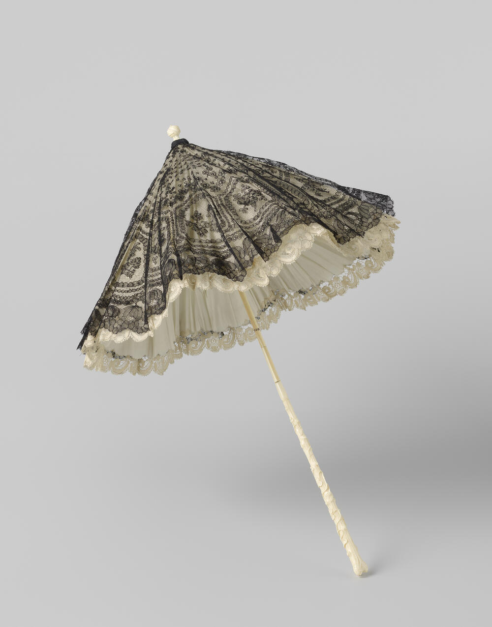 Parasol met een dek van zwarte Chantilly-kant op witte tafzijde, gevoerd met witte ponjézijde,…