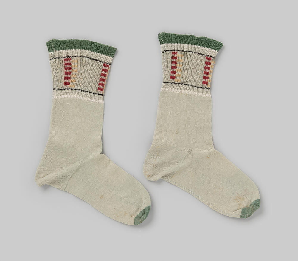 Sok van lichtgroene, fijne katoenen tricot, met in de boord een meegebreid blokpatroon in rood en…