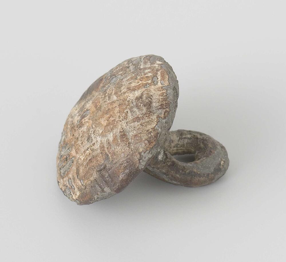 Knoop, rond afgeplat met decoratief patroon