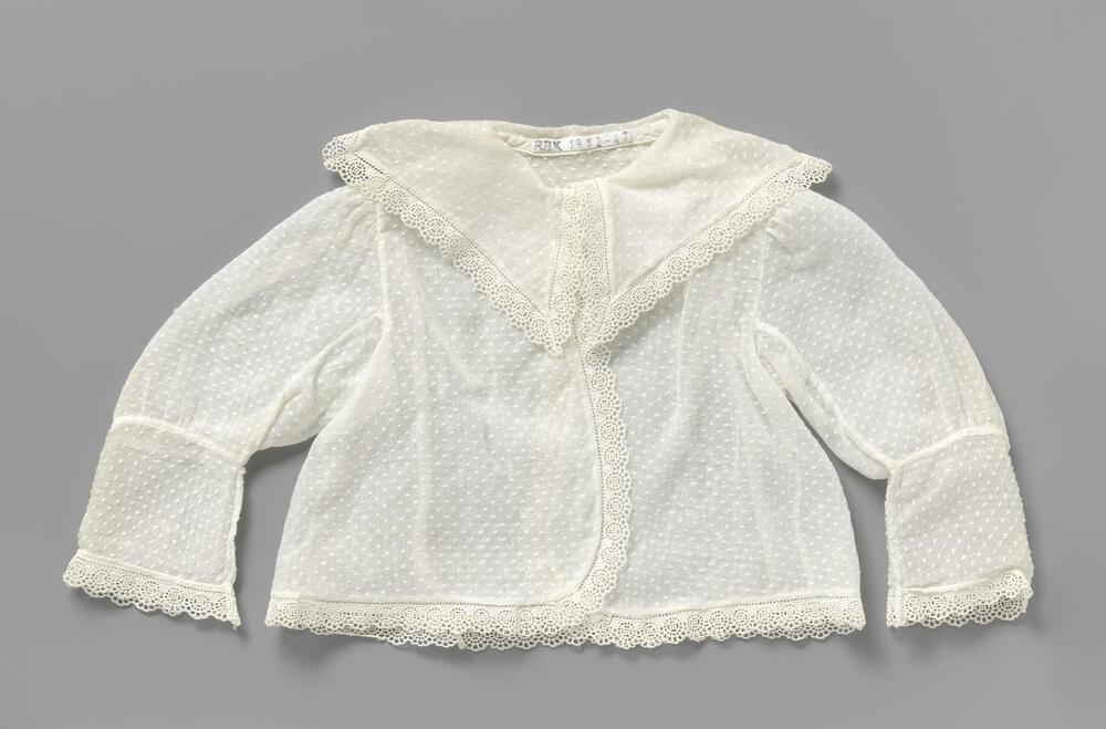 Grof batisten babyjas met ingeweven nopjes en afgezet met een smalle rand broderie