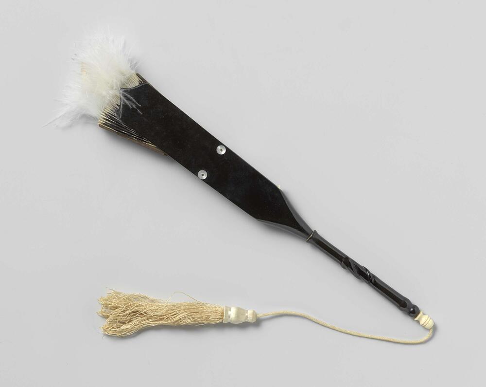 Kokardewaaier met cirkelvormig blad van witte batist met zwarte kantstrook en witte maraboeveertjes…