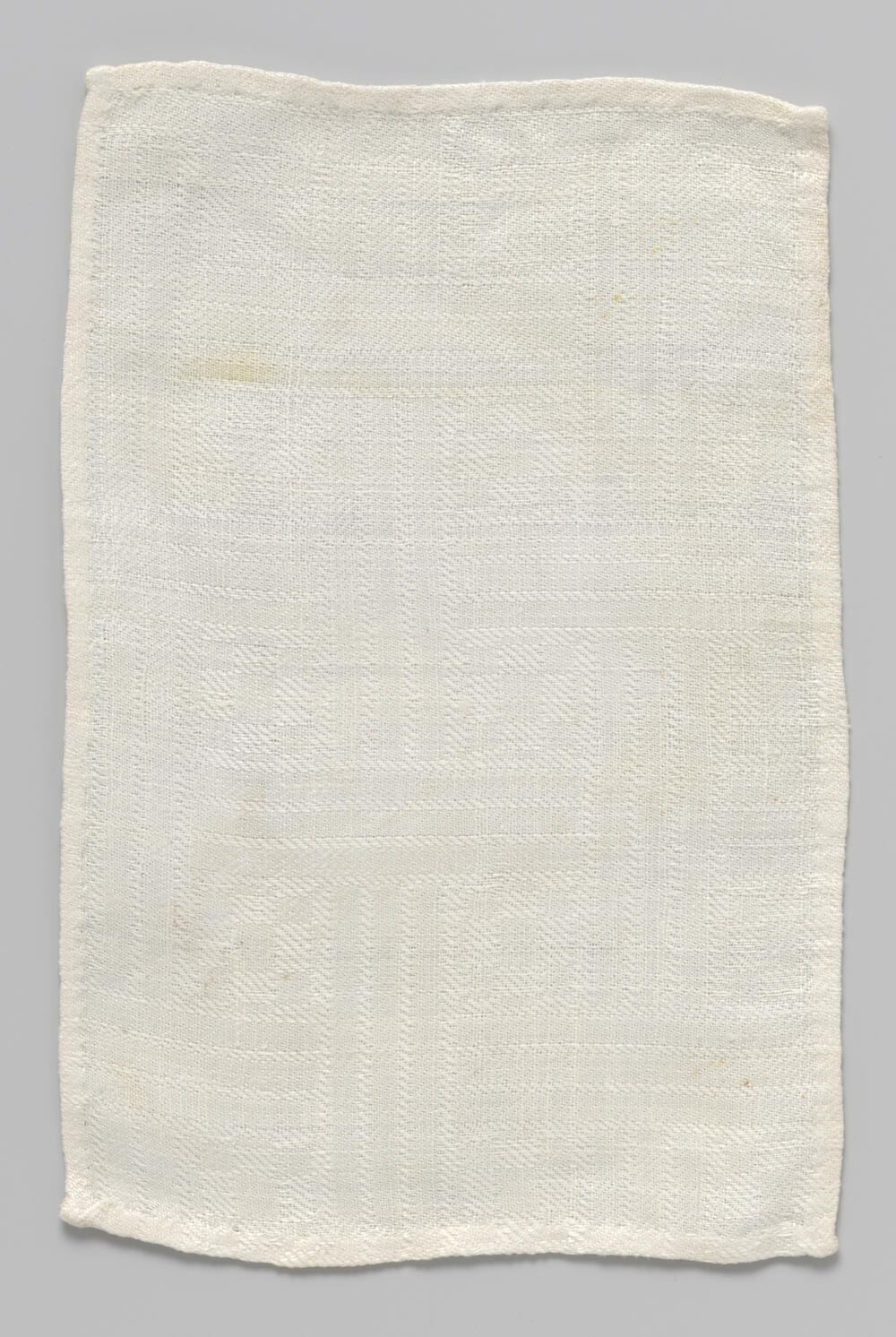 Witte rechthoekige doek met ingeweven geometrisch patroon
