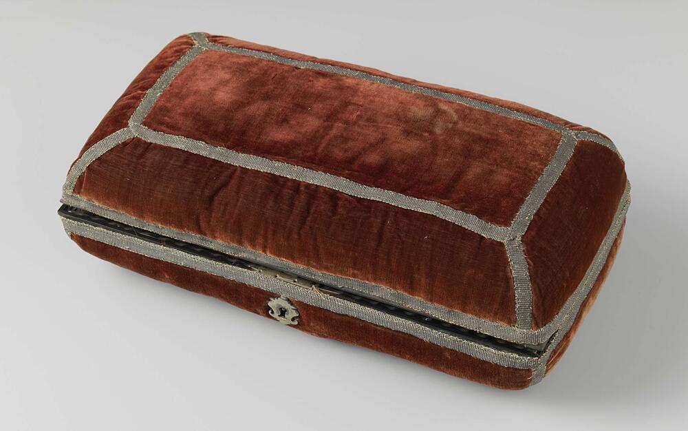 Langwerpig kussen bestaande uit twee gelijke helften, bekleed met rood fluweel versierd met…