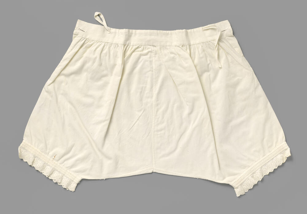 Witte katoenen onderbroek met pijpen, versierd met oprijgen, waartussen gestileerde wit geborduurde…