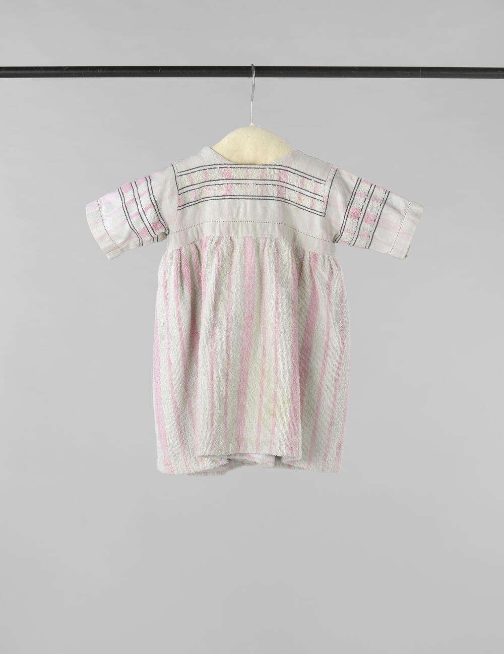 Kinderjurk met korte mouw, gemaakt van een wit-roze gestreepte badstoffen handdoek, op het lijf…
