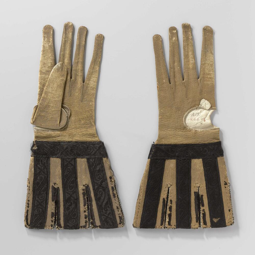 Handschoen van geiten(?)leer, okerkleurig geverfd met ingesneden, losse kappen versierd met zwart…