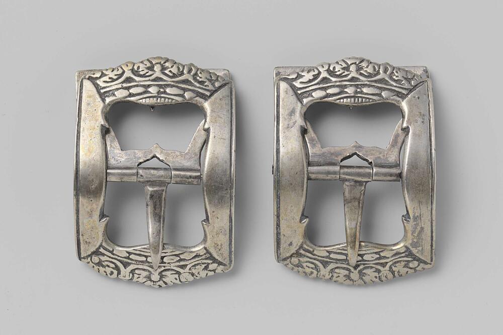 Schoengesp van zilver, waarvan de zijkanten de vorm van een kroon hebben, in vlak reliëf