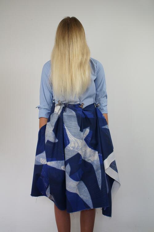 model met blond haar en met rug naar ons toe. Stoffen rok blauwe kleuren
