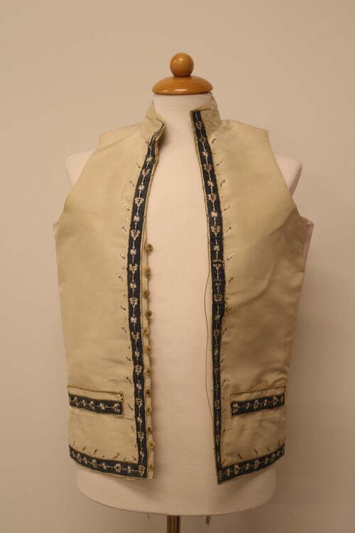 mouwloos vest;  met grauwblauwe bloemversiering